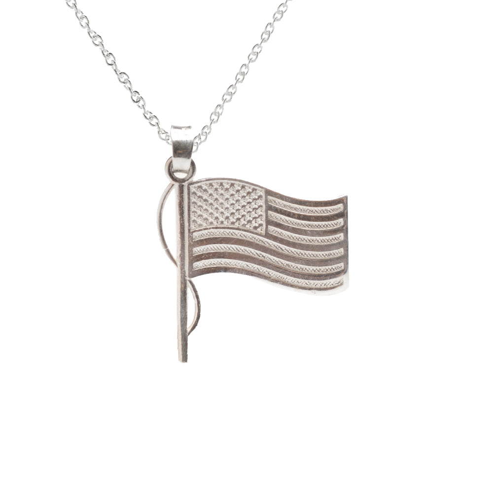 The Sterling Silver USA Flag Pendant Necklace features a detailed waving US flag with stars and stripes, accented by a vertical flagpole on a delicate chain for an elegant patriotic look.