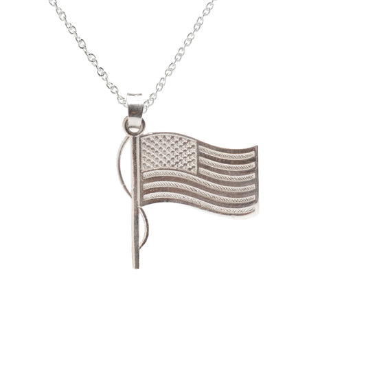 The Sterling Silver USA Flag Pendant Necklace features a detailed waving US flag with stars and stripes, accented by a vertical flagpole on a delicate chain for an elegant patriotic look.