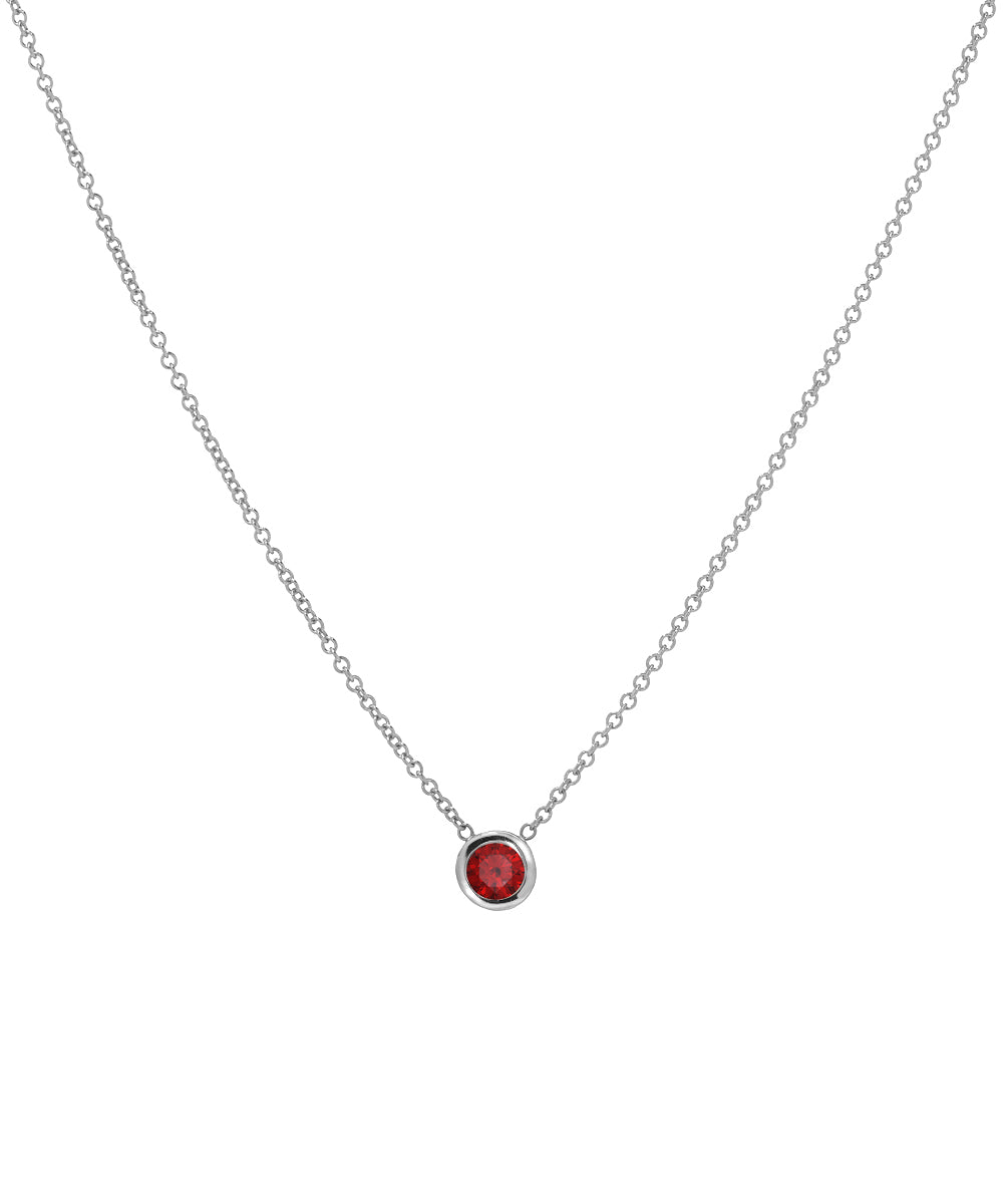 The 14KT White Gold 3 mm Bezel Solitaire Necklace features a small, round red gemstone in a simple bezel setting at the center of a 14K white gold chain.