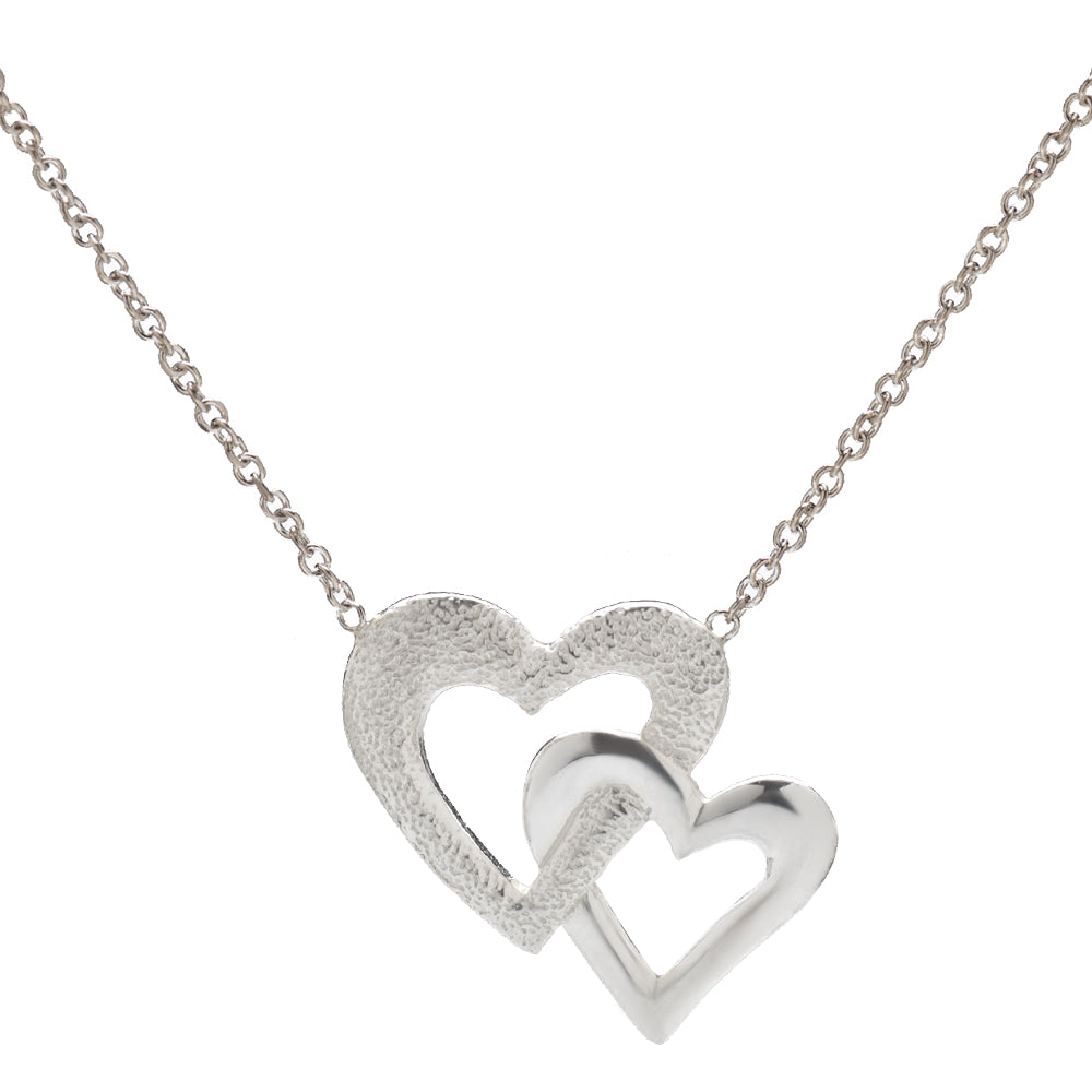 The Sterling Silver Double Heart Necklace, 18", features two interlocking hearts—one textured and one polished—in 925 sterling silver, elegantly suspended from a delicate chain against a white background.