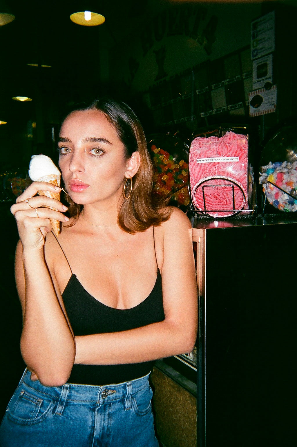 Model wearing Silver America 14 karat yellow gold hoops and rings holding and eating an ice cream cone. 